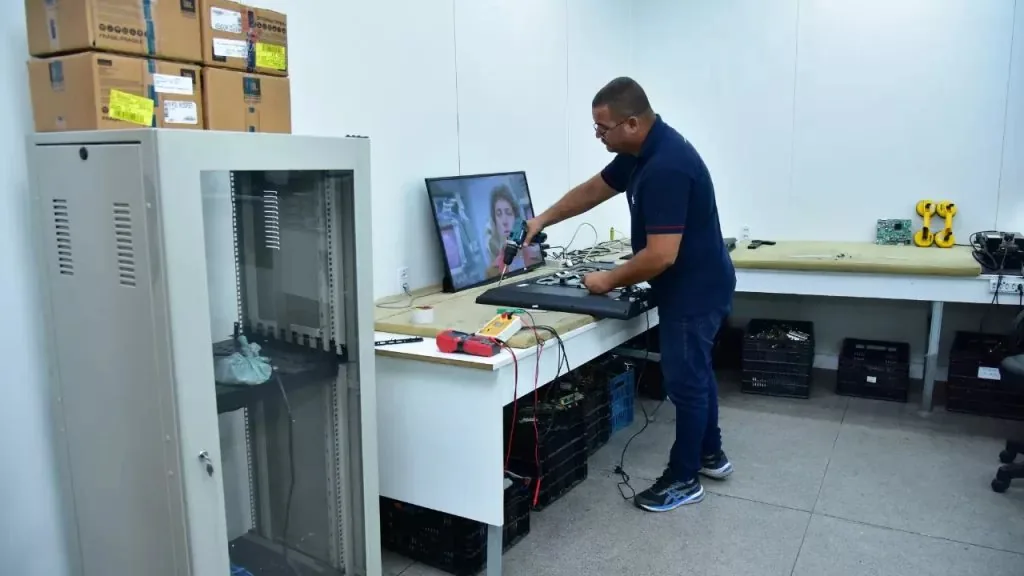 Técnico da Assintec reparando uma TV na bancada do laboratório