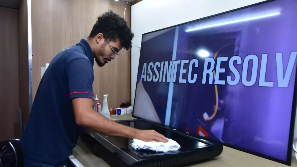 Técnico da Assintec cuidando de uma TV grande